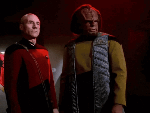two men standing next to each other with the words " y'all motherfuckers need kahless " in red letters