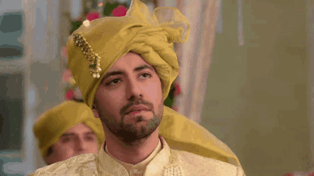 a man with a beard wearing a yellow turban and a white shirt