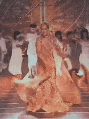a woman in a gold dress is dancing on a stage