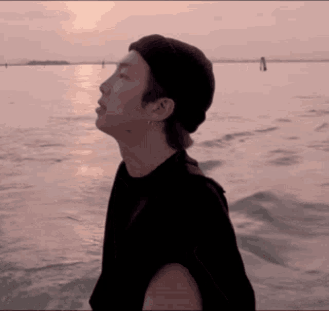 a man in a black hat stands in front of a large body of water