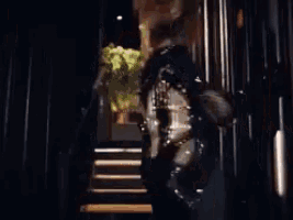 a woman is walking down a set of stairs holding a guitar .
