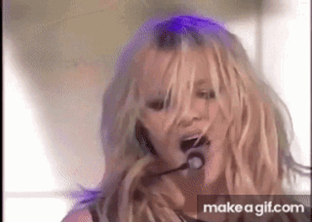 britney spears is singing into a microphone while wearing headphones .