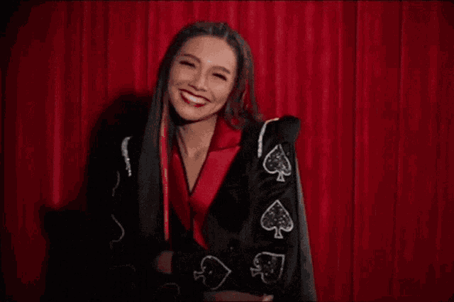 a woman is wearing a black jacket with spades on it .