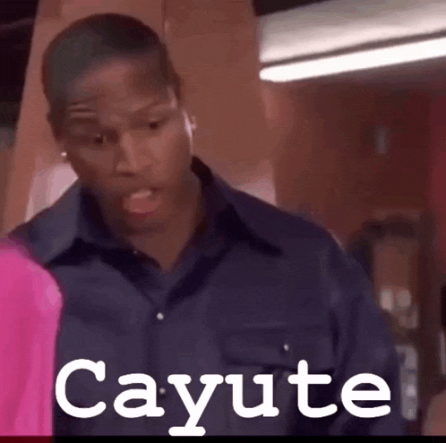a man in a blue shirt is standing in front of a sign that says cayote .
