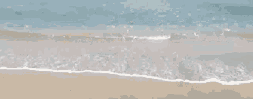 a blurry picture of a beach with waves crashing on it