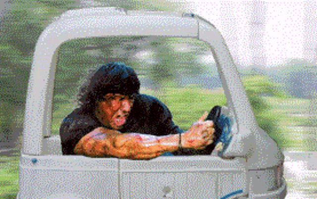a man with blood on his face is driving a small car