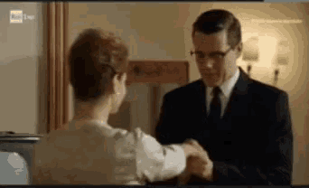 a man in a suit and tie shakes hands with a woman in a white shirt