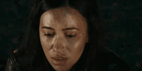 a close up of a woman 's face with water coming out of her hair in a dark room .