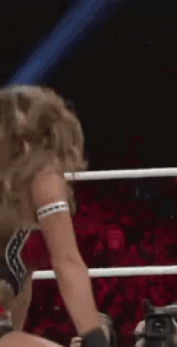 a woman is standing in a boxing ring with a camera in her hand .