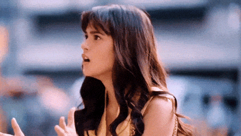 a woman with a surprised look on her face holds her hands up