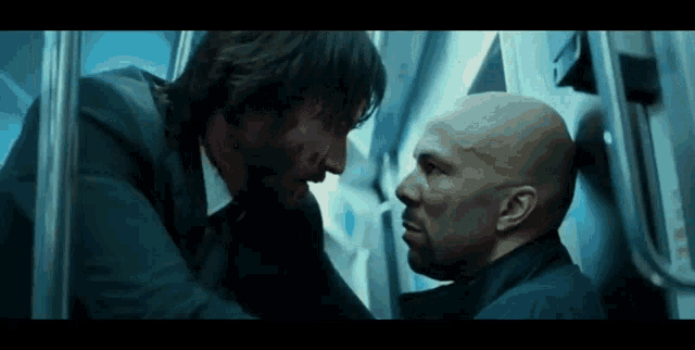 two men are standing next to each other in an elevator and looking at each other .
