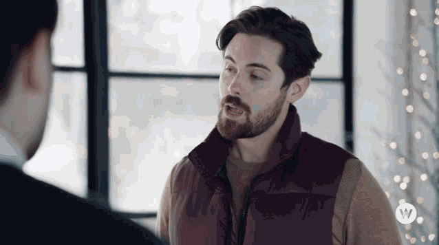 a man with a beard is wearing a purple vest with a w logo on the sleeve