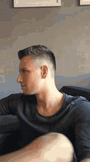a man is sitting on a couch with his legs crossed and looking at something .