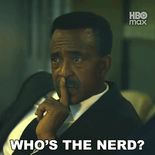 a man in a suit and tie is asking " who 's the nerd "