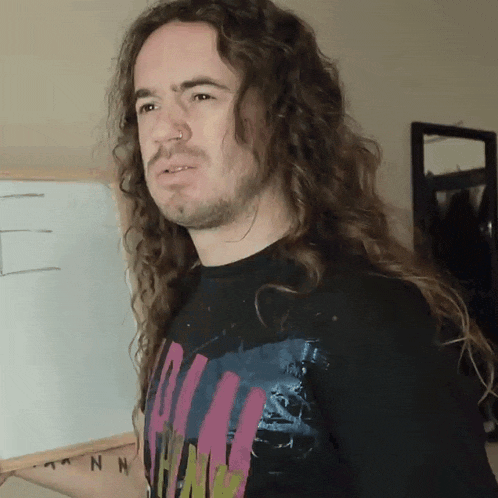 a man with long curly hair wearing a shirt that says ' nn ' on it