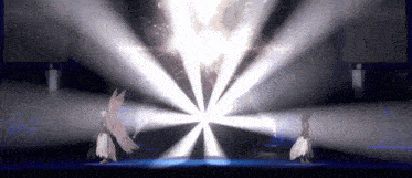 a couple of people standing on a stage with a light coming from the center