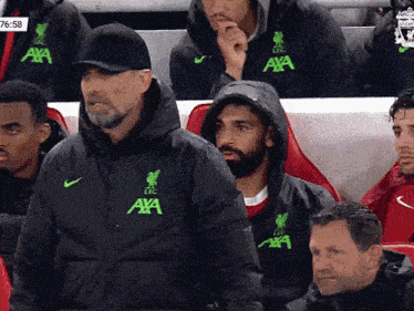 a group of men sitting in a stadium wearing jackets that say axa