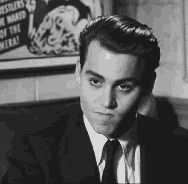 a man in a suit and tie is sitting in front of a poster that says bestlers
