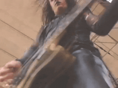 a man with long hair is playing a guitar on stage .