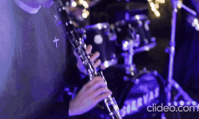 a close up of a person playing a clarinet with a cross on the shirt