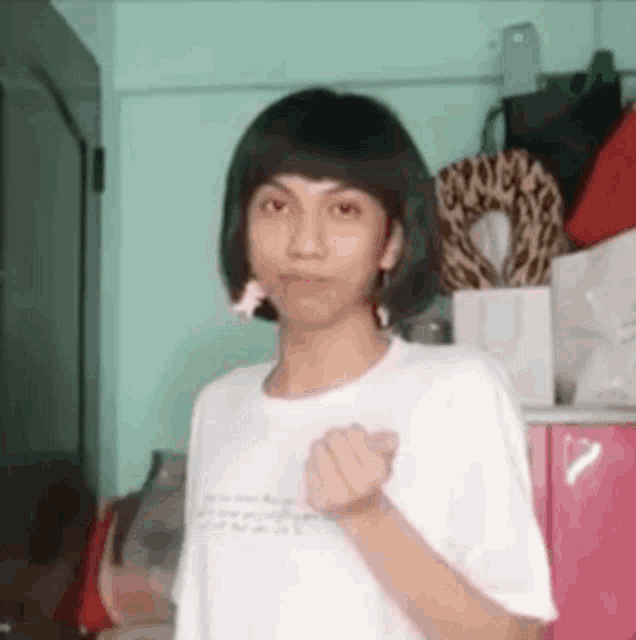 a young man with short hair is making a heart with his hand .