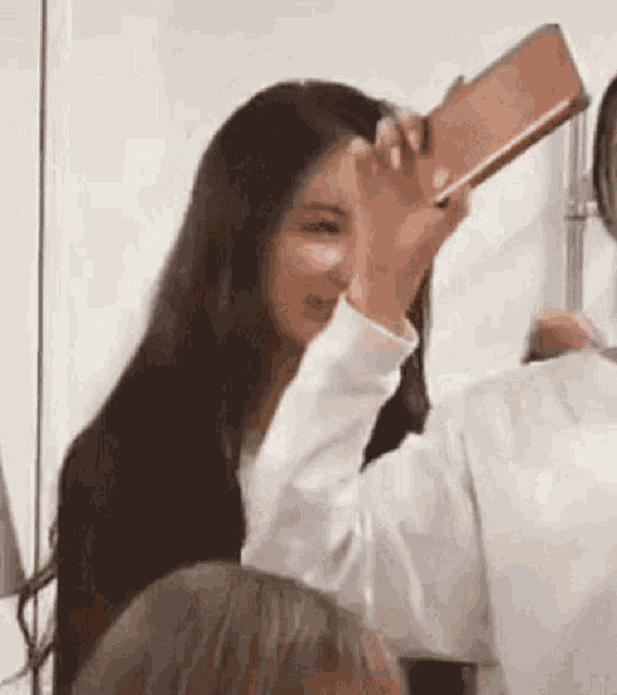 a woman is taking a selfie with a cell phone in front of her face .