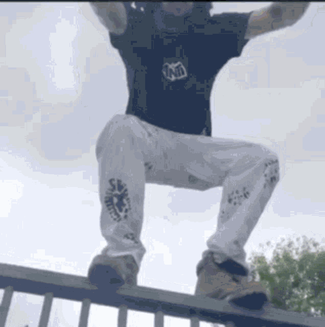 a man wearing a black shirt with the word tnt on it is jumping over a railing