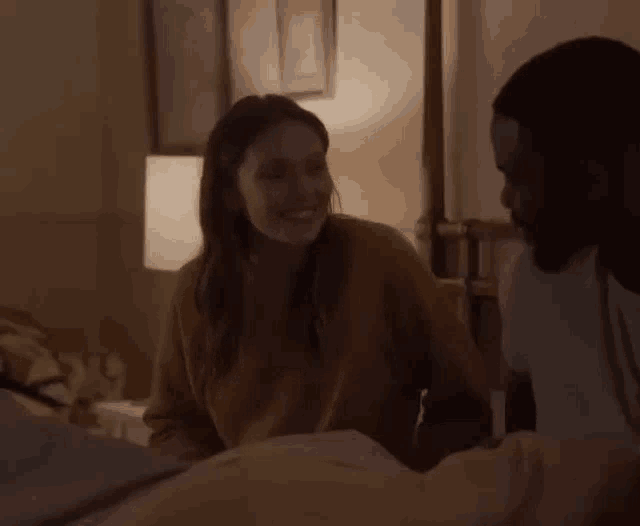 a man and a woman are sitting on a bed in a dark room .