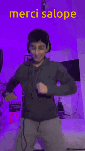 a man wearing headphones and a hoodie is dancing in a room with purple lights .