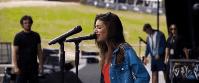a woman is singing into a microphone while standing on a stage