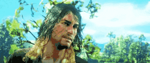 a man with long hair and a beard is standing in front of a tree .