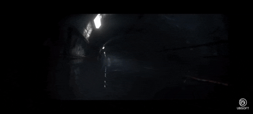 a man is standing in a dark room with a light shining through a window .