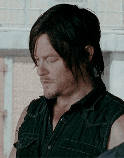 a man with a beard is wearing a black sleeveless shirt