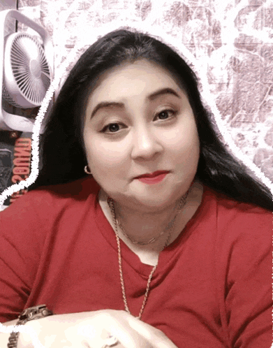 a woman wearing a red shirt has a white border around her face and a fan in the background