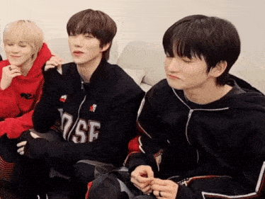 a group of young men are sitting on a couch and one of them is wearing a black jacket with the number 7 on it