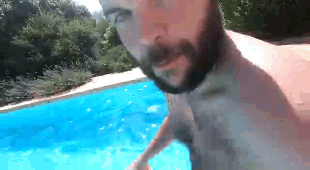 a shirtless man with a beard is standing in a pool .