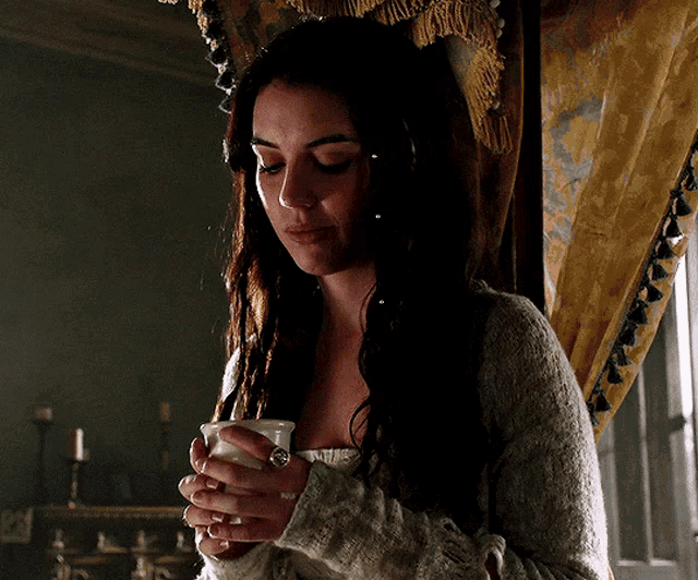 a woman in a white sweater is holding a white cup in her hands