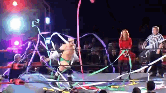 a man in a wrestling ring with a referee standing behind him