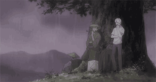 a group of people standing under a tree in a field .