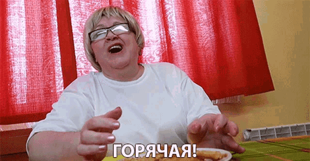 a woman with glasses is sitting at a table with a plate of food and the words " горячая " on the table