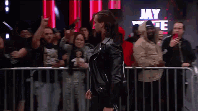 a crowd of people standing behind a fence watching a wrestler