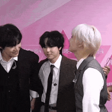 a man with white hair is kissing another man