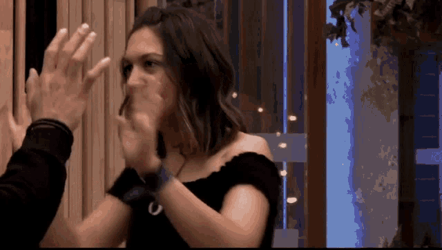 a woman in a black off the shoulder top gives a high five
