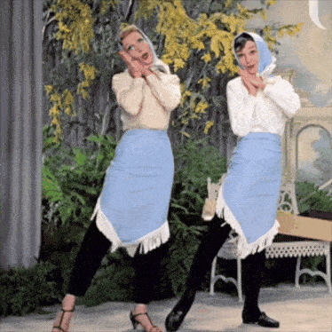 two women are standing next to each other and one is wearing a blue skirt with fringe