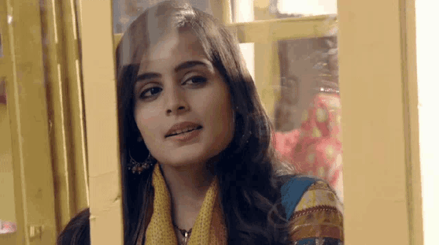 a woman is looking out of a window with a yellow frame