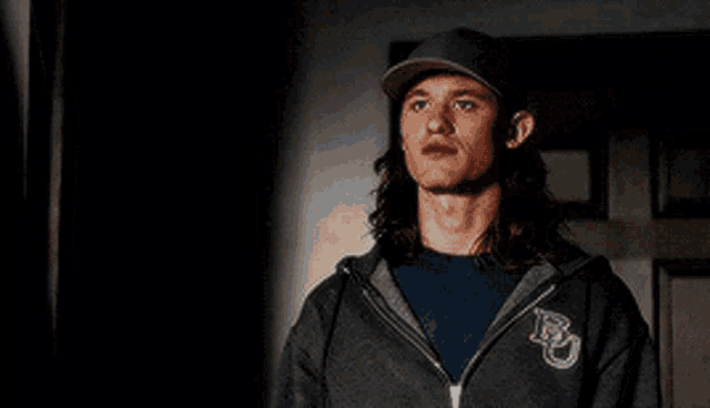 a man wearing a hat and a hoodie with the letter b on it