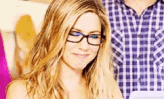 a woman wearing glasses and a plaid shirt is smiling and looking at the camera .