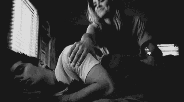 a man and a woman are laying on a bed and the woman is touching the man 's back .