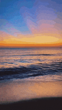 a sunset over a body of water with waves crashing on the beach