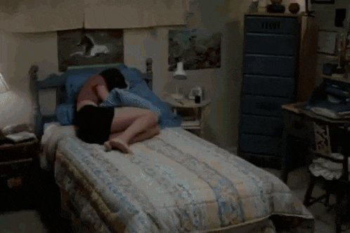 a person is sleeping on a bed in front of a window with the sun shining through the window .